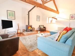 a living room with a blue couch and a fireplace at Packway Barn in Halesworth