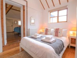 a bedroom with a white bed with towels on it at Packway Barn in Halesworth