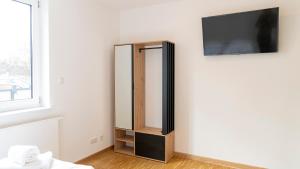 a room with a mirror and a tv on a wall at Henrys Sleeping am Augsburger Eiskanal in Augsburg
