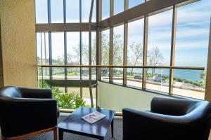 a waiting room with two chairs and a table and windows at Villa Graziadio Executive Center at Pepperdine University in Malibu