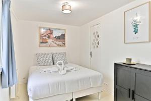 a bedroom with a white bed with a dresser at Appartement proche Canal Saint Martin in Paris