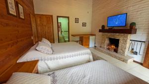 two beds in a room with a fireplace and a tv at Pousada Charme da Serra in Monte Verde