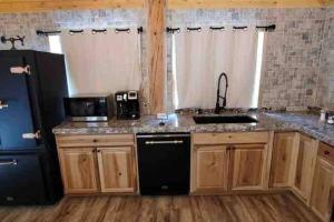 a kitchen with a sink and a black refrigerator at Brother Bear Lodge at Talkeetna in Talkeetna