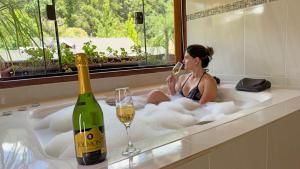 uma mulher sentada numa banheira com um copo de vinho em Pousada Charme da Serra em Monte Verde