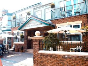 a brick building with umbrellas and tables and chairs at Dovedale Hotel and Restaurant in Cleethorpes