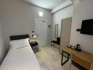 Schlafzimmer mit einem Bett, einem Schreibtisch und einem TV in der Unterkunft La Galleria Lodge in Parma