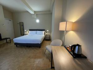 ein Schlafzimmer mit einem Bett, einem Stuhl und einem Tisch in der Unterkunft La Galleria Lodge in Parma