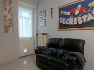 LELLO'S HOUSE في تورينو: أريكة جلدية سوداء في غرفة المعيشة مع ملصق فيلم