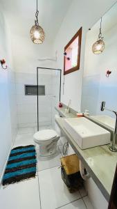 a white bathroom with a sink and a toilet at Pousada Bilica in Arraial d'Ajuda