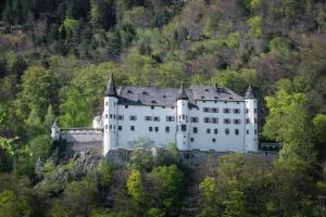 un gran castillo blanco en una colina con árboles en Ferienwohnung Maria & Luis, en Kolsass