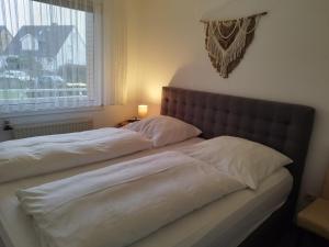 ein Bett mit zwei weißen Kissen und einem Fenster in der Unterkunft Strandperle in Westerland