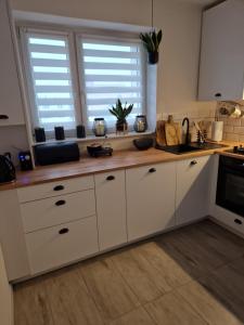 une cuisine avec des placards blancs et un comptoir en bois dans l'établissement PIK-Kwatery, à Morąg