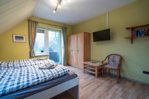 Schlafzimmer mit einem Bett, einem TV und einem Stuhl in der Unterkunft Stellmann’s Gästehof in Bruchhausen-Vilsen