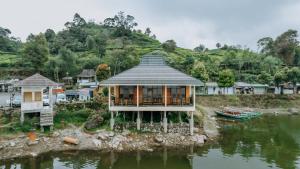 une maison sur une île dans l'eau dans l'établissement Villa Situ Patenggang, à Ciwidey