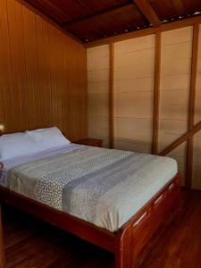 Cama en habitación con paredes de madera y suelo de madera. en Casa en Misahualli - Misahualli HOME, en Puerto Misahuallí