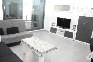 sala de estar con sofá, mesa y TV en Apartamento Capri 4 Inmomart, en Peñíscola