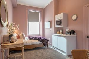 a bedroom with a bed and a table and a kitchen at Boutique Home Stay Blossom in Paisley