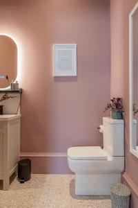 La salle de bains est pourvue de toilettes blanches et d'un lavabo. dans l'établissement Boutique Home Stay Blossom, à Paisley
