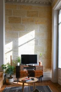 a living room with a tv and a brick wall at Appartement gare Saint jean in Bordeaux