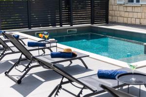 a pool with two chairs and a table next to a swimming pool at Villa Nono in Dubrovnik