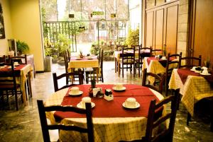a restaurant with tables and chairs with red and white table cloth at Hotel Mayoral in Rosario