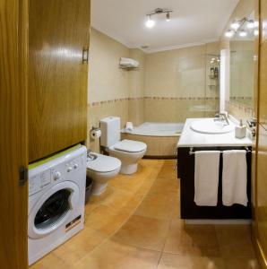 a bathroom with a toilet and a sink and a washing machine at Vacaciones en O Grove in O Grove