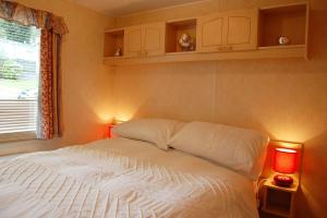 a bedroom with a white bed with two lights at Caravan B26 at The Woodlands in Tywyn