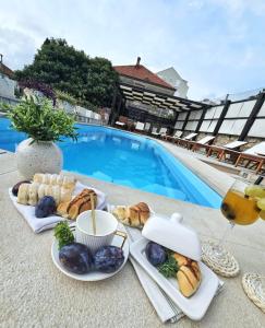 a table with plates of food next to a swimming pool at Apartments Miljas in Dubrovnik