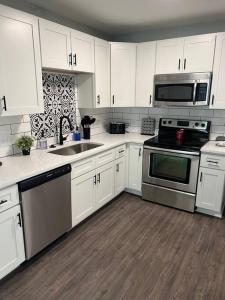 una cocina con armarios blancos y electrodomésticos de acero inoxidable en Newly renovated cute 3 bedroom 2 bath bungalow, en Charlotte