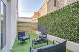 a patio with chairs and a table and a green wall at 801 Suite Luxurys - Superbe Appartement in Bagnolet