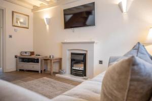 a living room with a fireplace with a tv on the wall at Pebbles Cottage, Southwold in Southwold