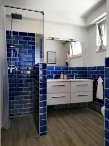 baño con paredes de azulejos azules y lavabo en Happy Apartments, en Balatonlelle