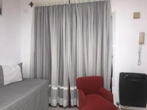 1 dormitorio con 1 cama y 1 silla roja en Departamento Libertad en Puerto Madryn