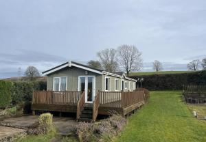 a small house with a porch and wooden decks at Natland Caravan Park in Kendal