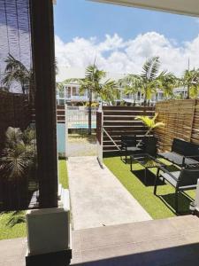 Elle offre une vue sur une terrasse avec des chaises et des palmiers. dans l'établissement Duplex climatisé avec piscine, à Saint-Pierre