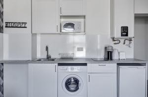 a white kitchen with a washing machine and a sink at 803 Suite Parisian - Superbe appartement in Bagnolet