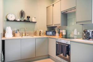 a kitchen with white cabinets and a clock on the wall at Boutique Home Stay - Bliss Studio in Paisley