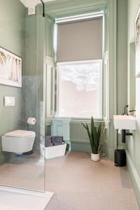 a bathroom with a toilet and a sink and a window at Boutique Home Stay - Bliss Studio in Paisley