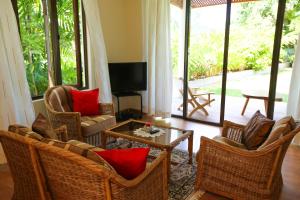 a living room with chairs and a table and a tv at Villa Voilier in Mahe