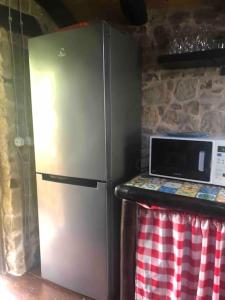 een roestvrijstalen koelkast in een keuken met een magnetron bij San Noto casina di caccia con piscina riscaldata 