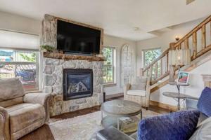 - un salon avec une cheminée en pierre et une télévision dans l'établissement Cabin~Views~Heart of Town~W&D~Fireplace~Kitchen, à Woodland Park