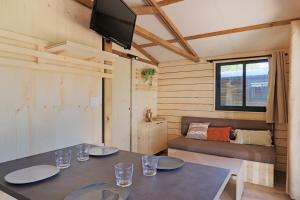 a room with two tables and a couch and a television at Camping les vergers de Squividan *** in Tréffiagat