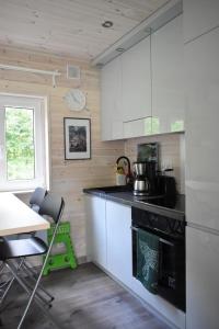 a kitchen with white cabinets and a table and a clock at Haus "Blücher" TinyHouse Mobilheim in Stuer