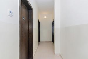 um corredor com uma porta de madeira e um piso branco em Collection O Krushna Rooms em Vagholi