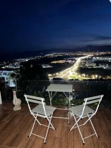 2 sillas y una mesa en el balcón por la noche en Luxueux VILLA avec jardin et vue panoramique, en Tetuán
