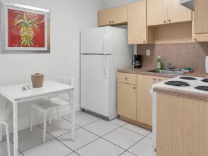 a kitchen with a white refrigerator and a table at South River Suites in Medley