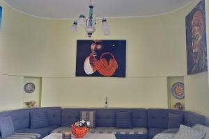 una sala de estar con un sofá azul y una pintura en la pared en 4US: A cosy glamour stay on the sea 4YOU!, en Vibo Valentia Marina