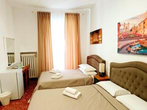 una camera d'albergo con due letti e uno specchio di A Casa Simpatia - Check-in Via Bixio, 41 a Roma