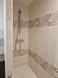 uma casa de banho com um chuveiro e uma parede em azulejo em Comme à la maison em Gannat
