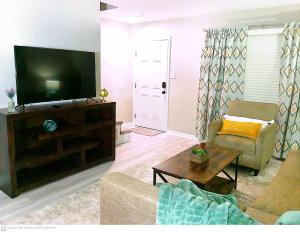 uma sala de estar com um sofá e uma televisão de ecrã plano em Liberty Towne em Fayetteville